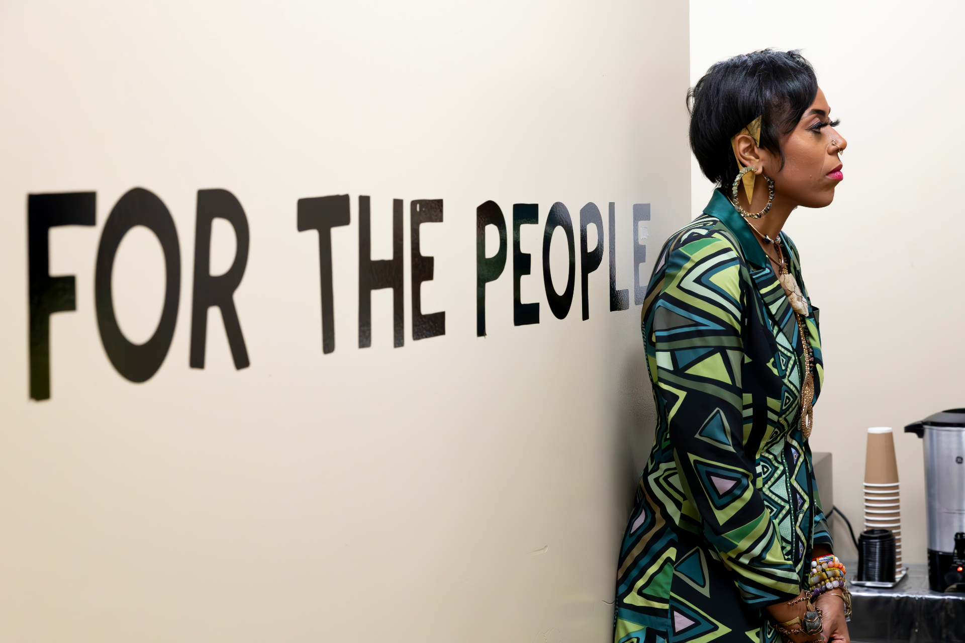 Christa standing beside a 'For the People' wall mural